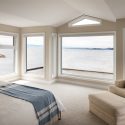 Waterfront bedroom in Oak Bay with simple window casings and millwork that keeps the focus on the view.