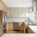 Warm and bright kitchen with natural wood lower cabinets and soft beige uppers, featuring a mix of textures and clean modern lines.